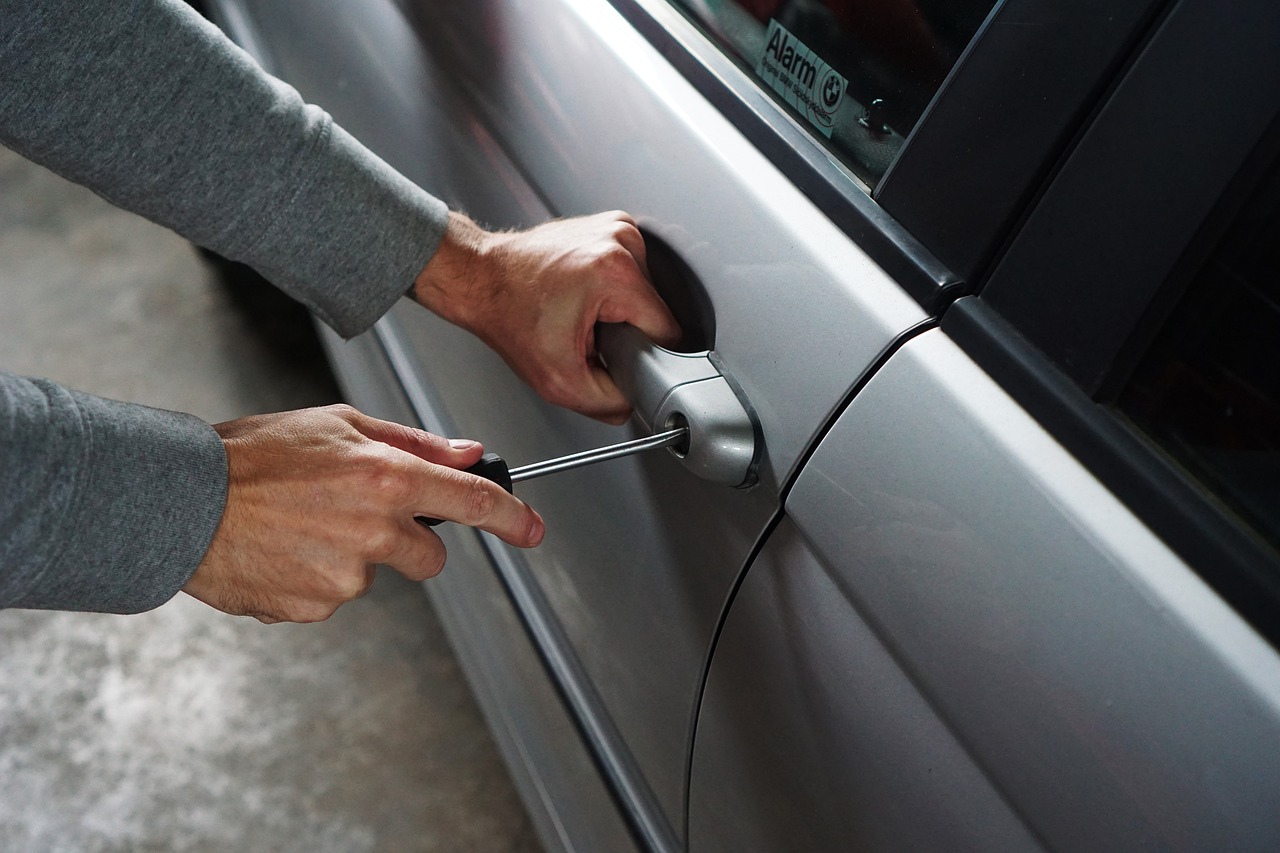 Man breaking into a car lock with a screwdriver