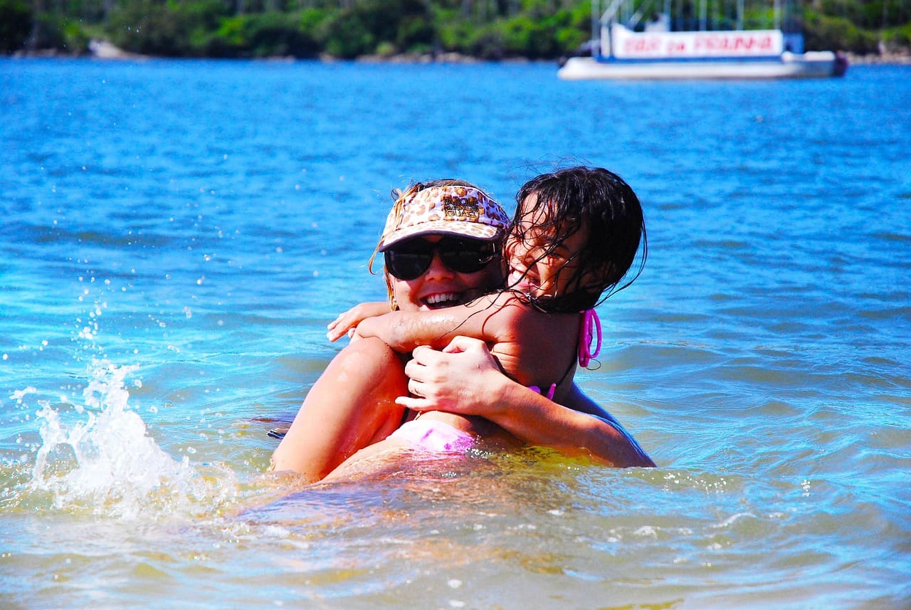 mom and kid in the open water as she teaches her daughter to be comfortable in the water.