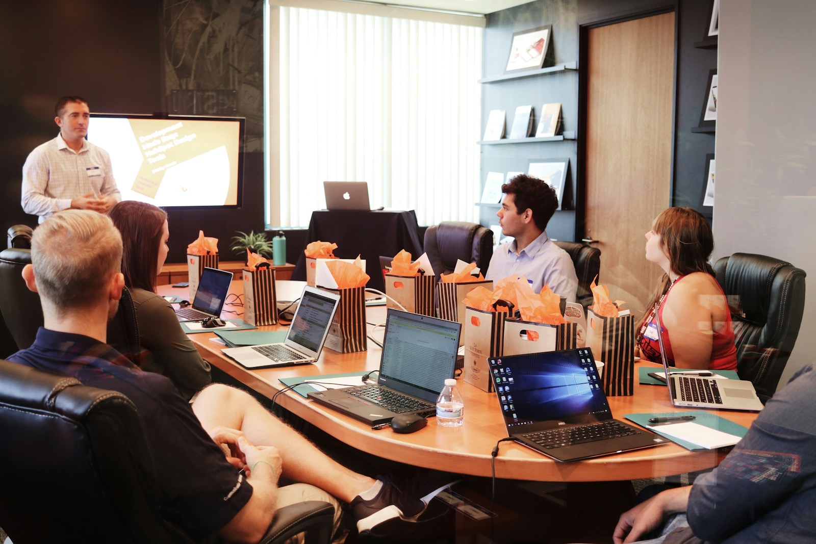 man standing in front of people sitting beside table with laptop computers, workers' compensation